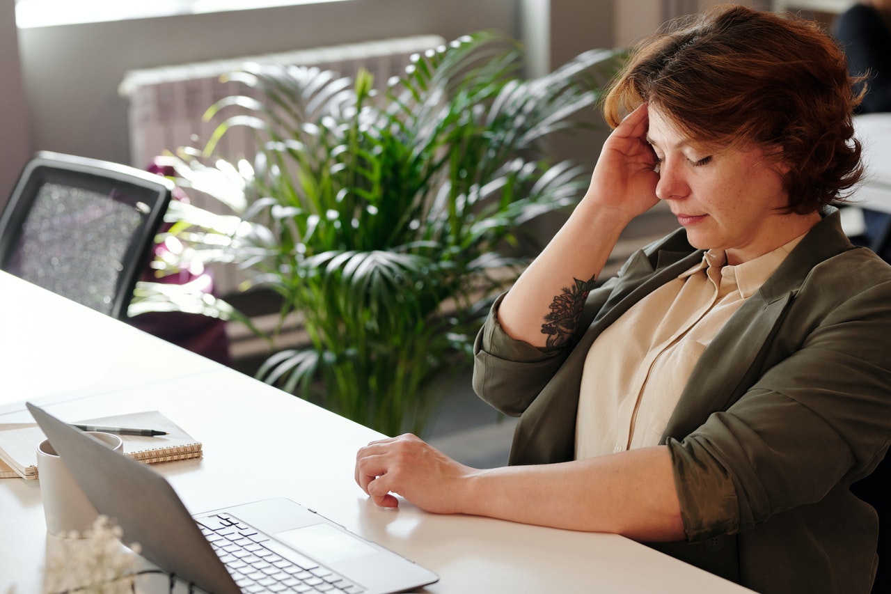 Woman sitting at desk appearing composed but mentally overwhelmed